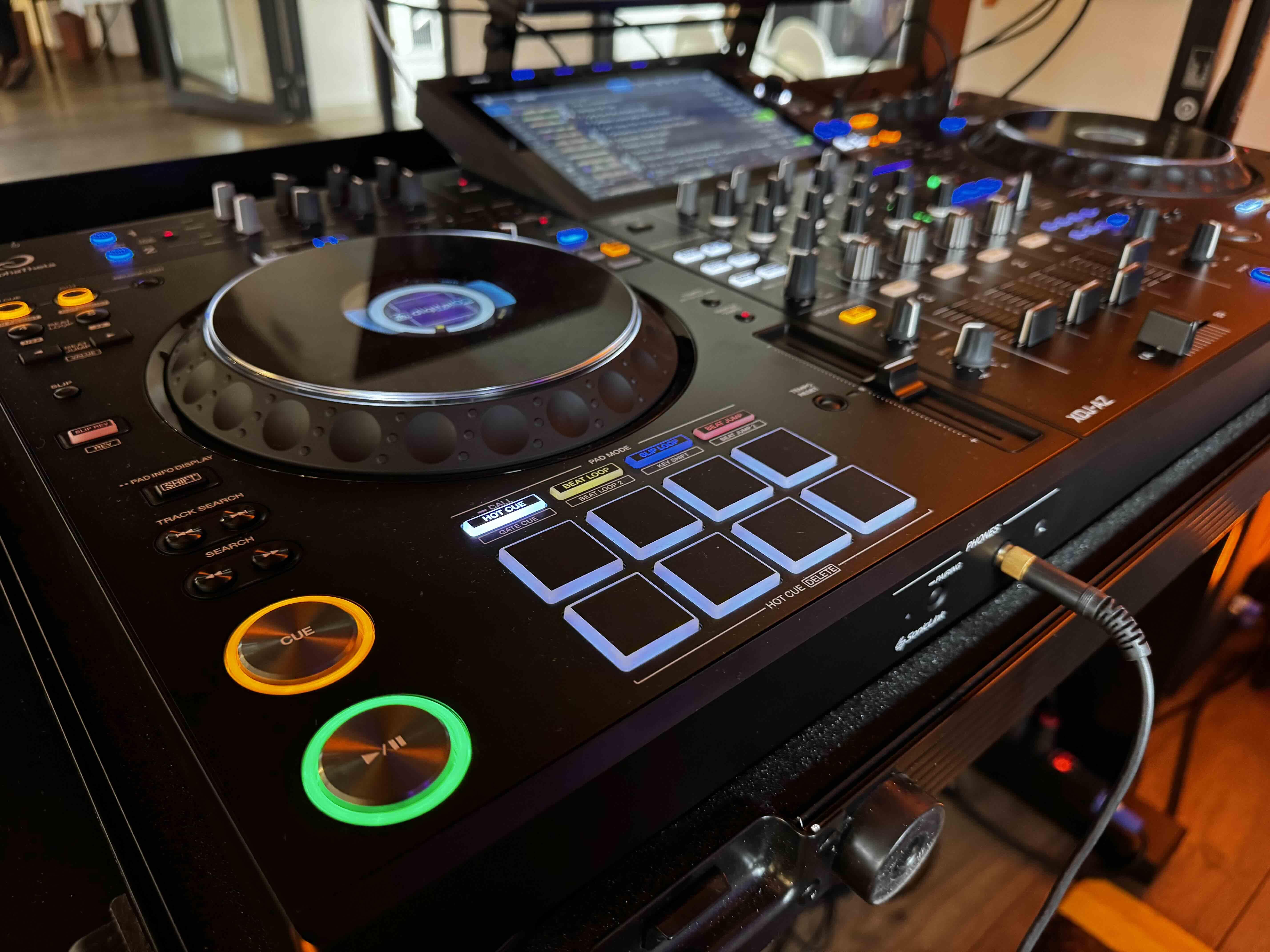 Zbliżenie konsolety DJ-skiej Braciaki z podświetlonymi przyciskami i mikserem